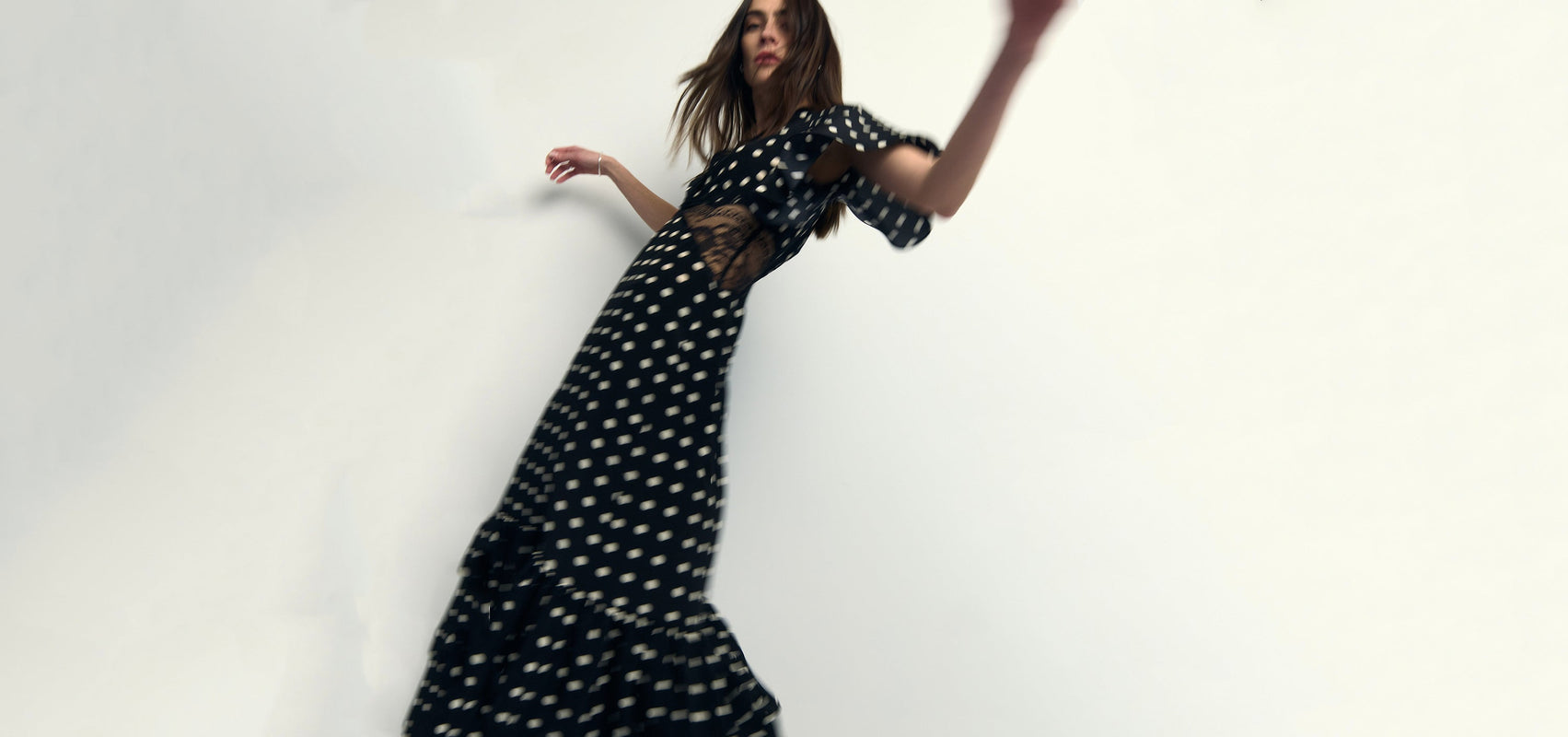 Woman wearing a black polka dot dress against a white background